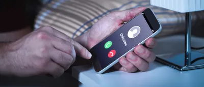 Hands holding a smartphone with an unknown caller identity