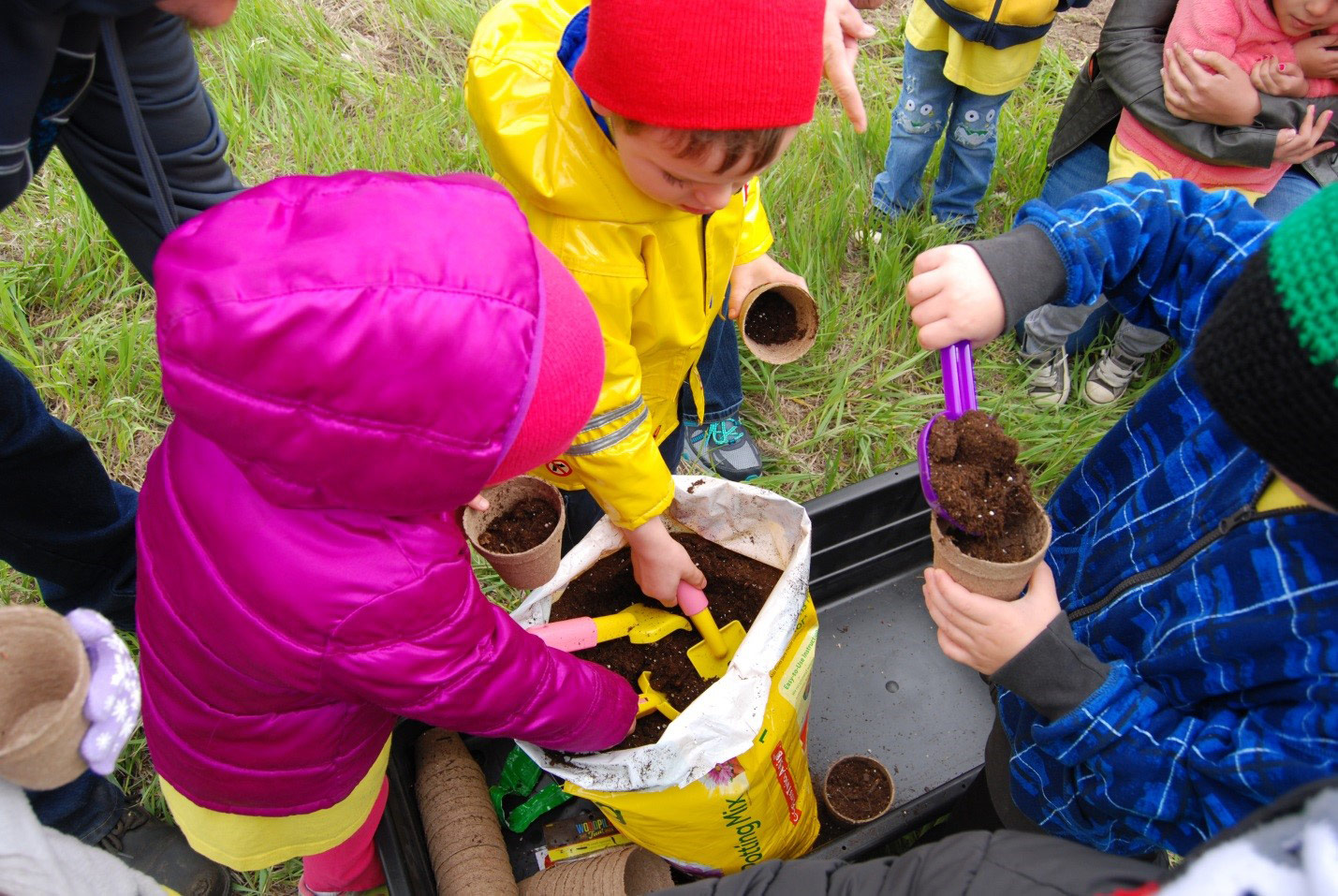 Children digging soil out of a pot for planting flowers