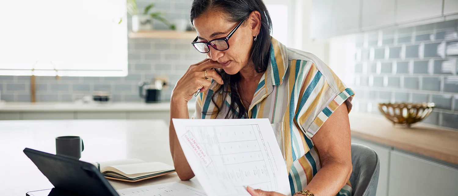 Individual looking at medical bills at kitchen table