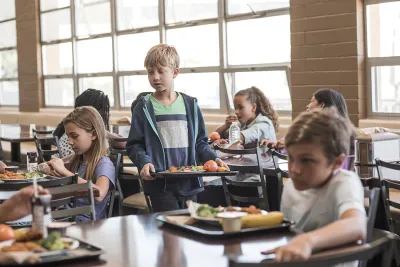 Child holding a lunch tray of food in a school cafeteria