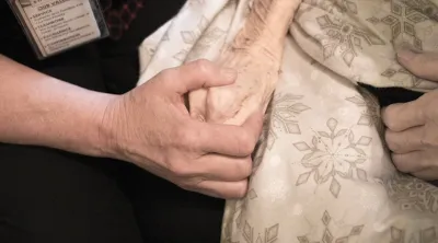 Blue Shield California palliative care worker holding the hand of a patient with cancer