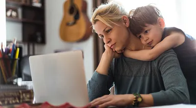 woman on computer with son hugging her