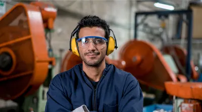 Mechanic in shop with arms crossed wearing earmuffs