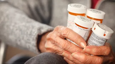 Senior citizen holding bottles of prescription medications