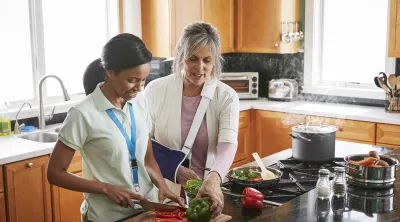 Caregiver slicing vegetables with patient