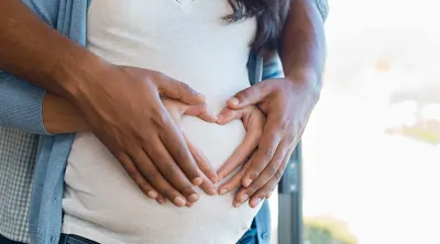 Pregnant couple with hands on woman's belly