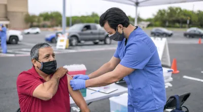 man getting a shot in a parking lot by a healthcare professional