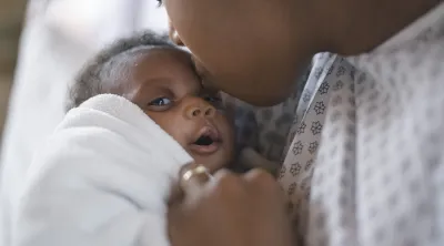 A Black women holds her newborn baby.