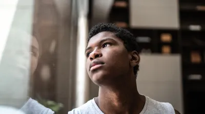 A Black youth states at his distorted reflection. In Hispanic and African American communities, major depression is often underdiagnosed and undertreated.