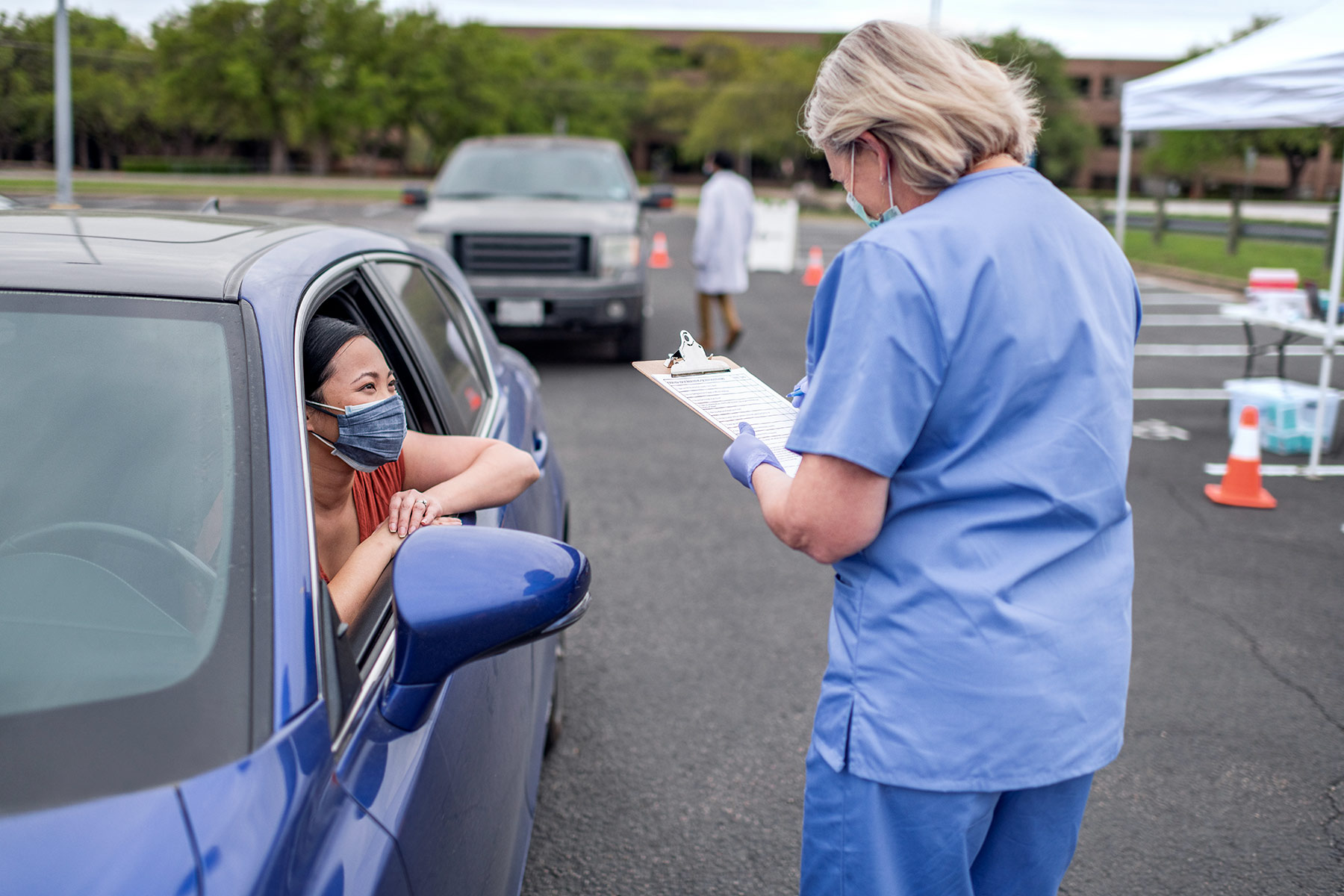 A nurse outside chatting with a patient in her car